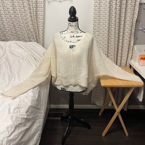 Cream batwing sweater.  Hits at waist.